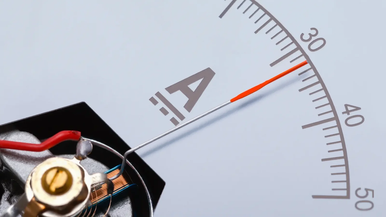 A close-up view of an analog DC ammeter with a needle indicator pointing to approximately 30 amperes. The internal components, including wiring and a coil mechanism, are visible, highlighting the precision engineering of the device.